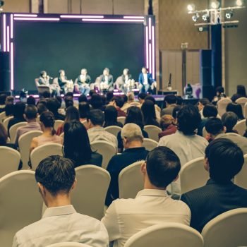 Rear view of Asian audience joining and listening group of speaker talking on the stage in the seminar meeting room or conference hall, business and education, associate and startup business concept